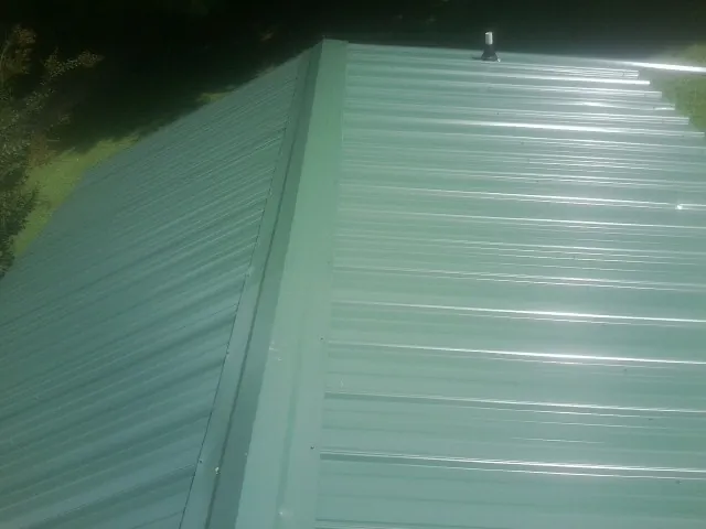 New green metal panels meeting at the ridge of a roof — Flat Roof Repair work by our crew in Round Rock