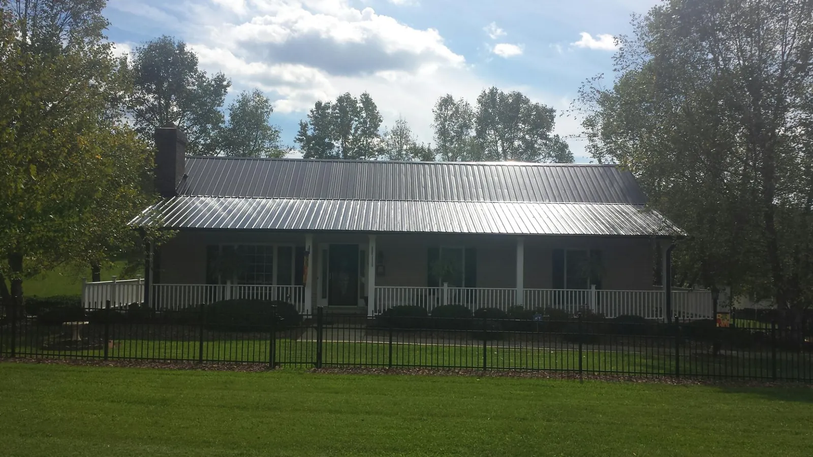 Gray metal roof on a brick ranch with a full width front porch — Gutter Guard Installation work by our crew in Round Rock