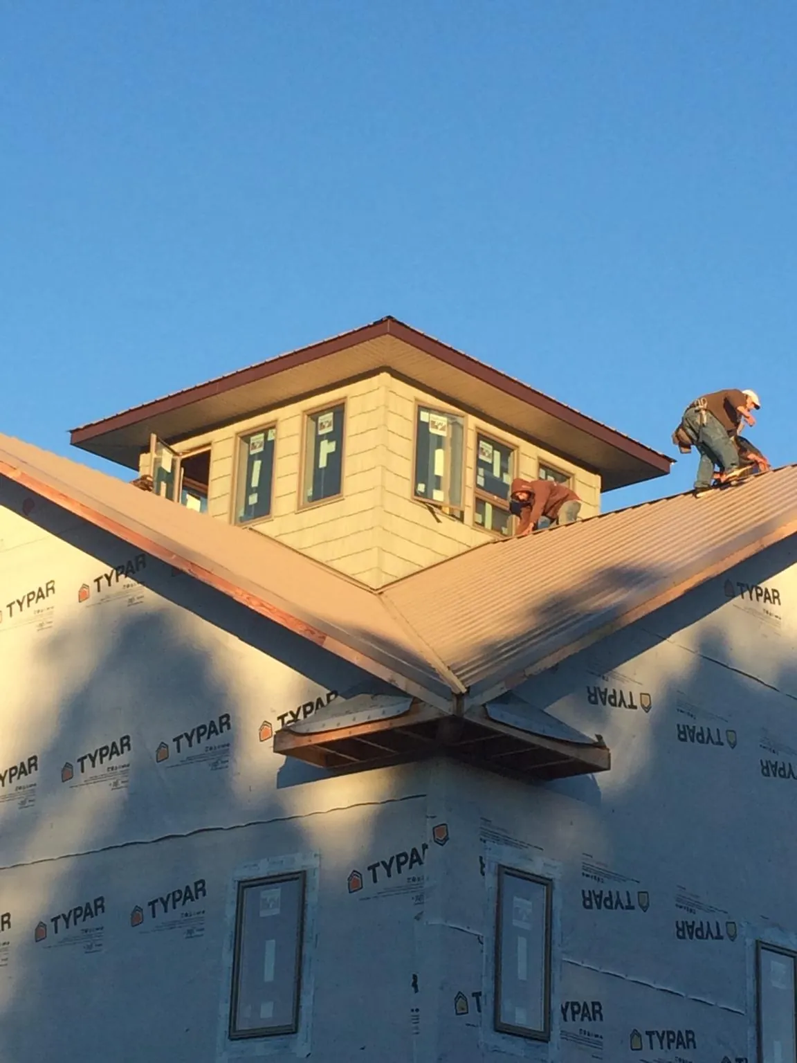 Roofers working around a rooftop cupola on a new metal roof at sunset — Roof Waterproofing in Round Rock by Roofing Brothers